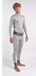 Ein Jugendlicher mit hellbraunem Haar steht barfuß und lächelt in die Kamera. Er trägt ein passgenaues Diston WC Schnittfeste Hosen Herren - 4FIS Stars in CRG - CORE / Racing Fit Set: ein hellgraues langärmeliges Oberteil und eine passende schnittfeste Unterhose mit Diston-Branding.
