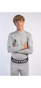 Ein junger Mann mit lockigem blondem Haar trägt eine Diston WC Schnittfeste Hosen Herren - 4FIS Stars in CRG - CORE / Racing Fit und ein dazu passendes hellgraues langärmeliges Oberteil. Er lächelt mit verschränkten Armen vor einem schlichten weißen Hintergrund.