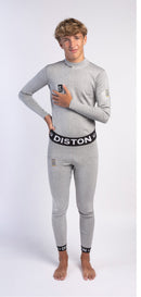 Ein junger Mensch mit hellbraunem Haar steht barfuß auf weißem Untergrund und lächelt selbstbewusst in Diston WC Schnittfeste Hosen Herren - 4FIS Stars in CRG CORE / Racing Fit-hellgraue schnittfeste Unterhose mit "DISTON" auf Bund und Bündchen, ideal für Skirennläufer.