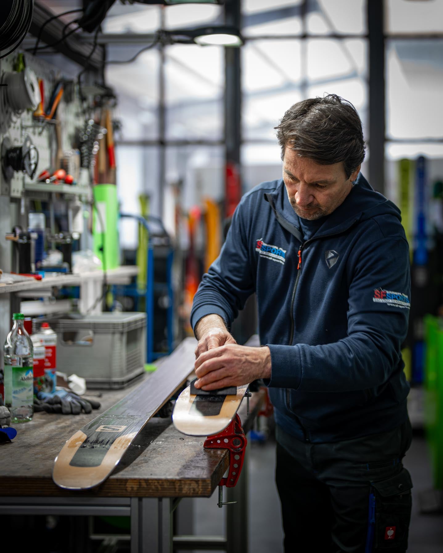 Ein Skiservice bei SF Sports, bei dem der alte Belag von einem Ski abgetragen wird, um ihn auf das Auftragen von frischem Wachs vorzubereiten. Die präzise Arbeit sorgt für optimale Gleitfähigkeit und verlängert die Lebensdauer des Skis.