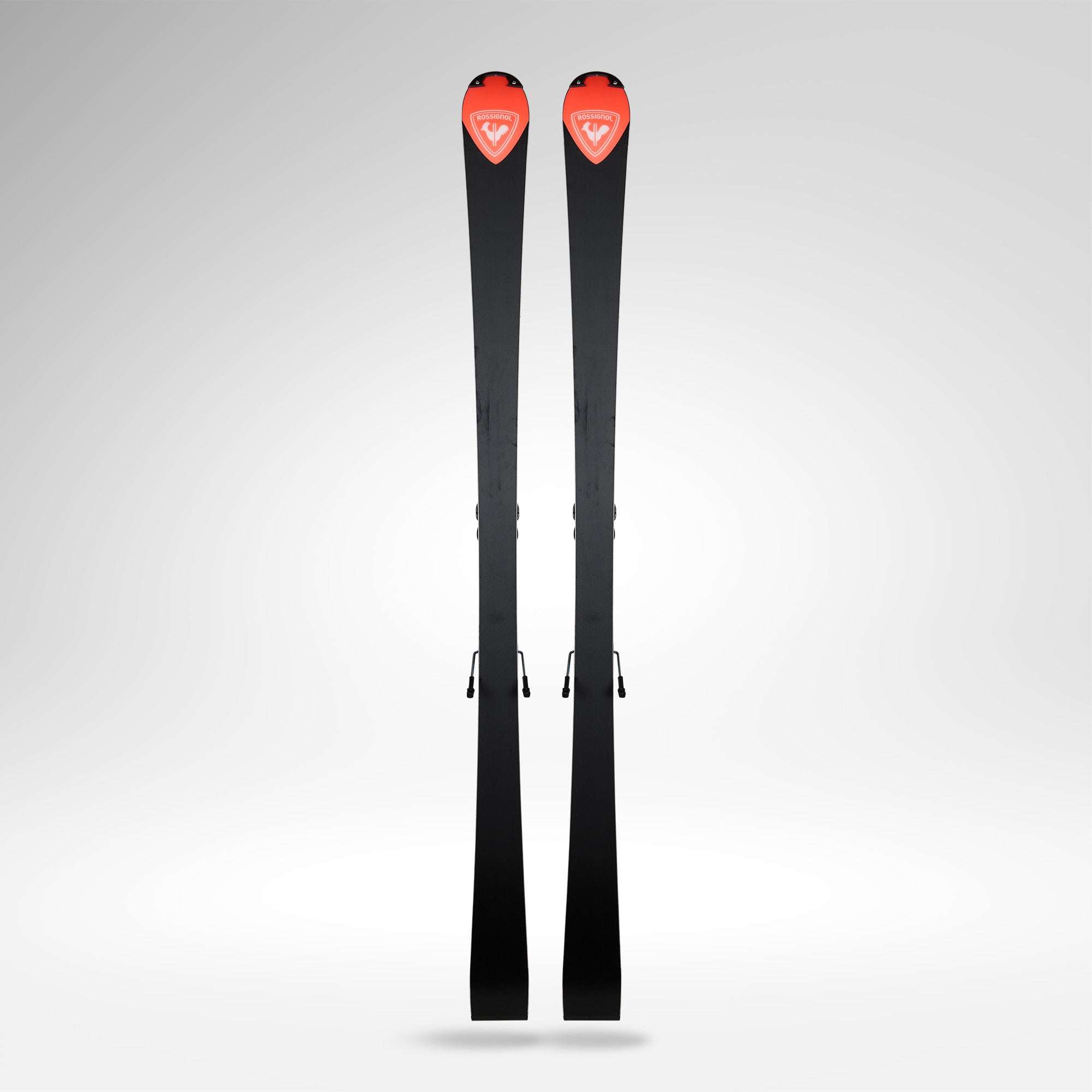 Ein Paar Rossignol HERO FIS SL FAC 165 R22 2026/2027 von Rossignol mit roten Akzenten und weißem Logo im Spitzenbereich steht aufrecht vor einem schlichten, hellgrauen Hintergrund.