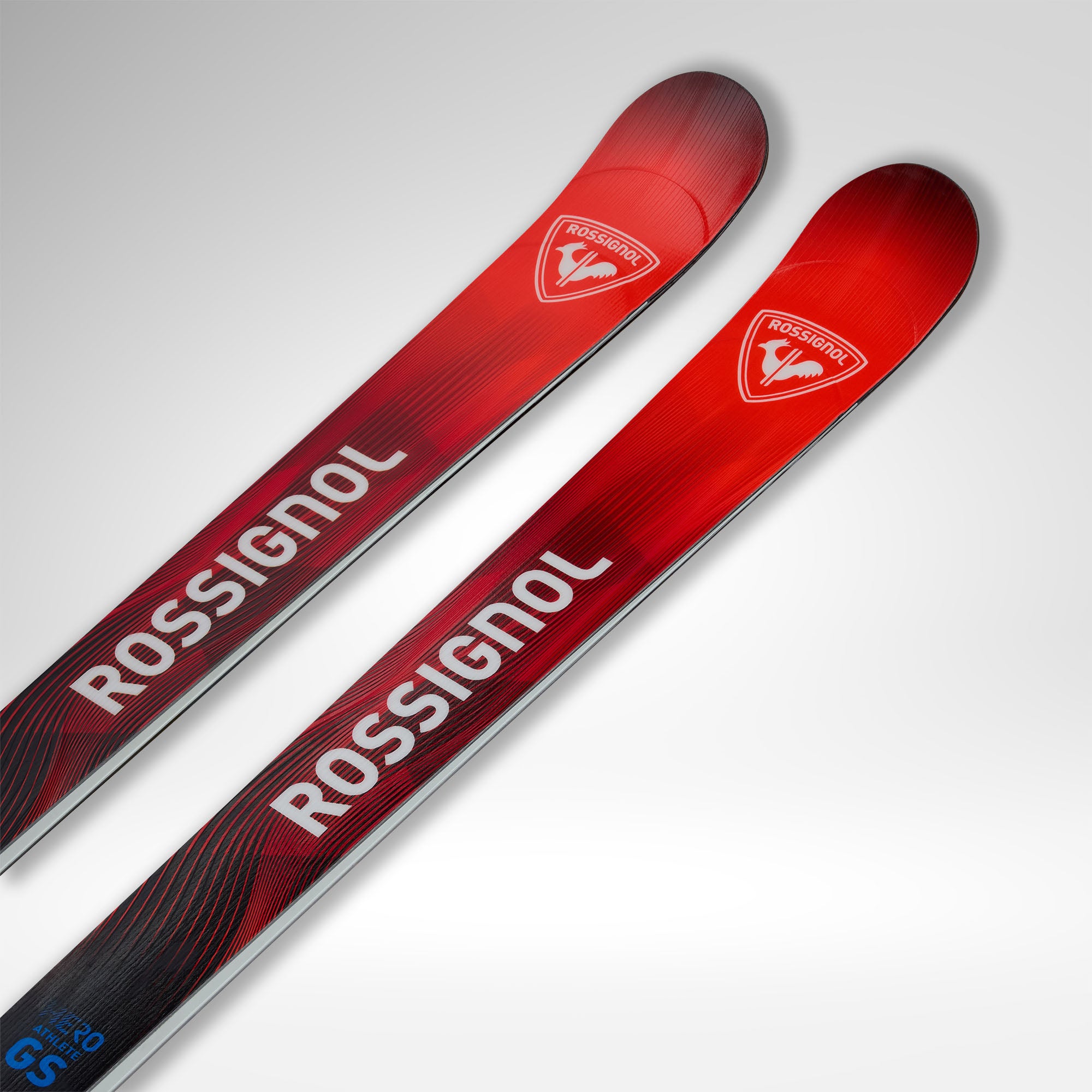 Ein Paar Rossignol HERO ATHLETE GS R22 2026/2027 Skier für U14 U16, mit rotem und schwarzem Farbverlauf mit diagonalen Akzenten, weißem Rossignol Branding und hellgrauem Hintergrund.