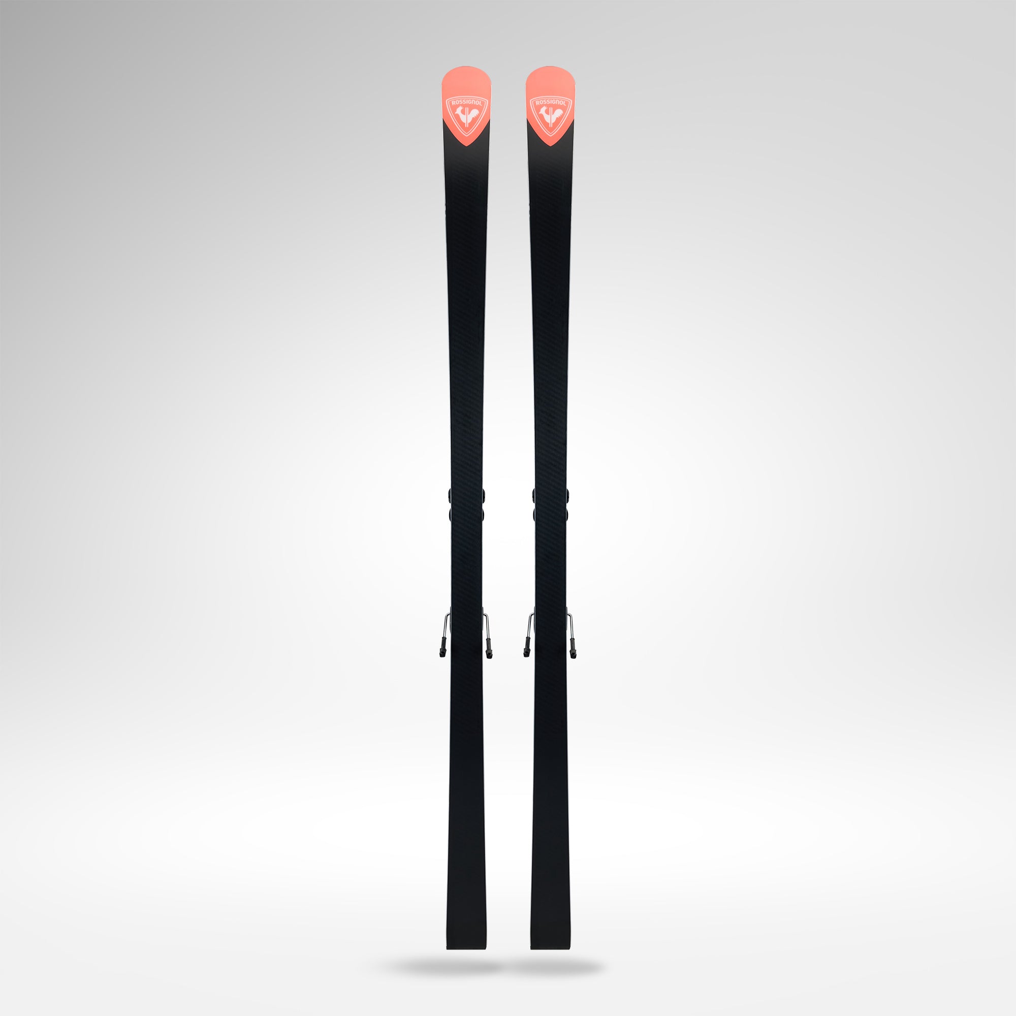 Ein Paar schwarze Rossignol HERO ATHLETE GS R22 2026/2027 Skier mit roten Spitzen und weißem Logo, entworfen für U14 U16 Riesenslalom-Rennski, steht aufrecht vor einem schlichten hellgrauen Hintergrund.