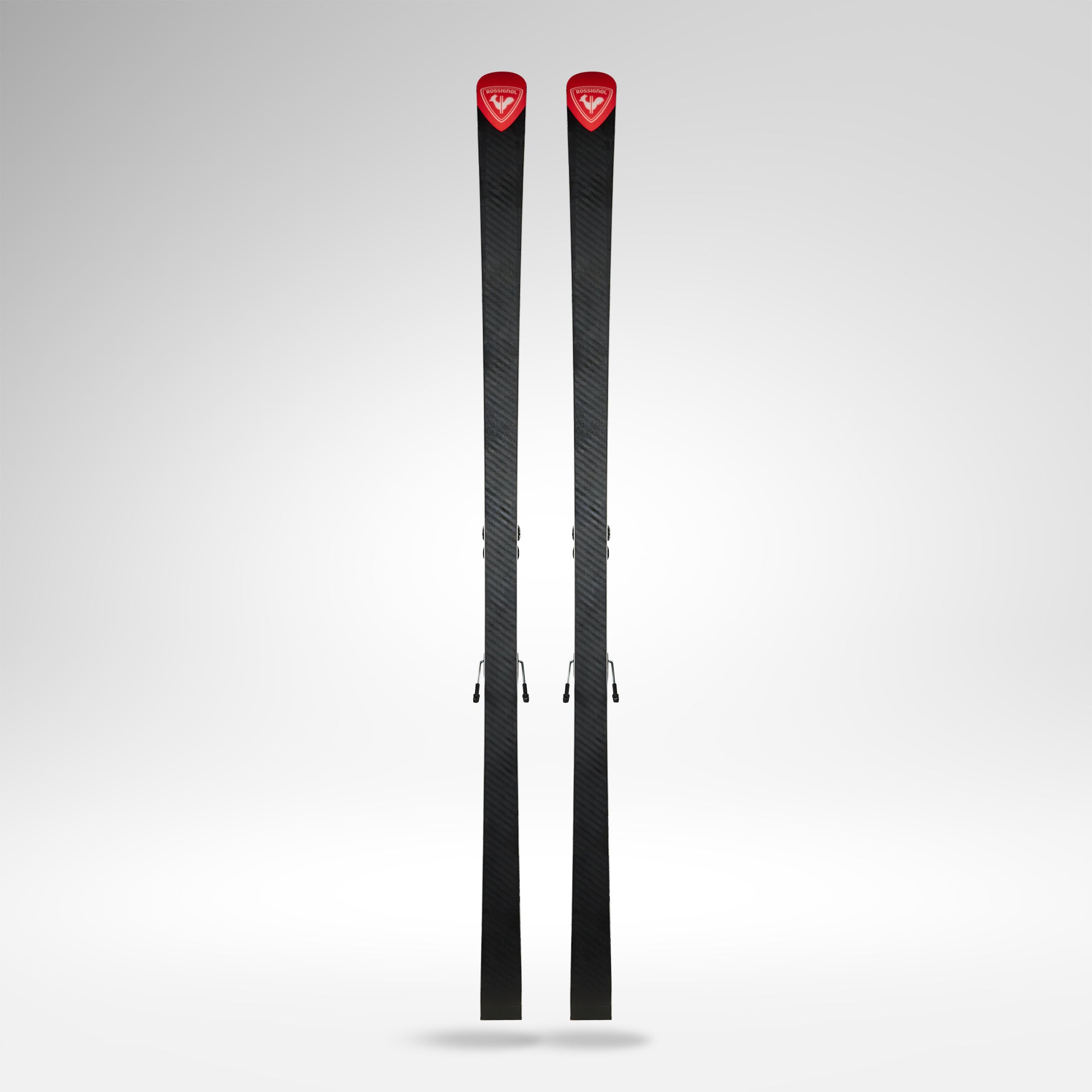 Ein Paar Rossignol HERO ATHLETE GS 185 R22 2026/2027 Skier, schwarz mit Strukturmuster und roten Spitzen mit weißem Logo, stehen aufrecht vor einem einfarbigen hellgrauen Hintergrund.