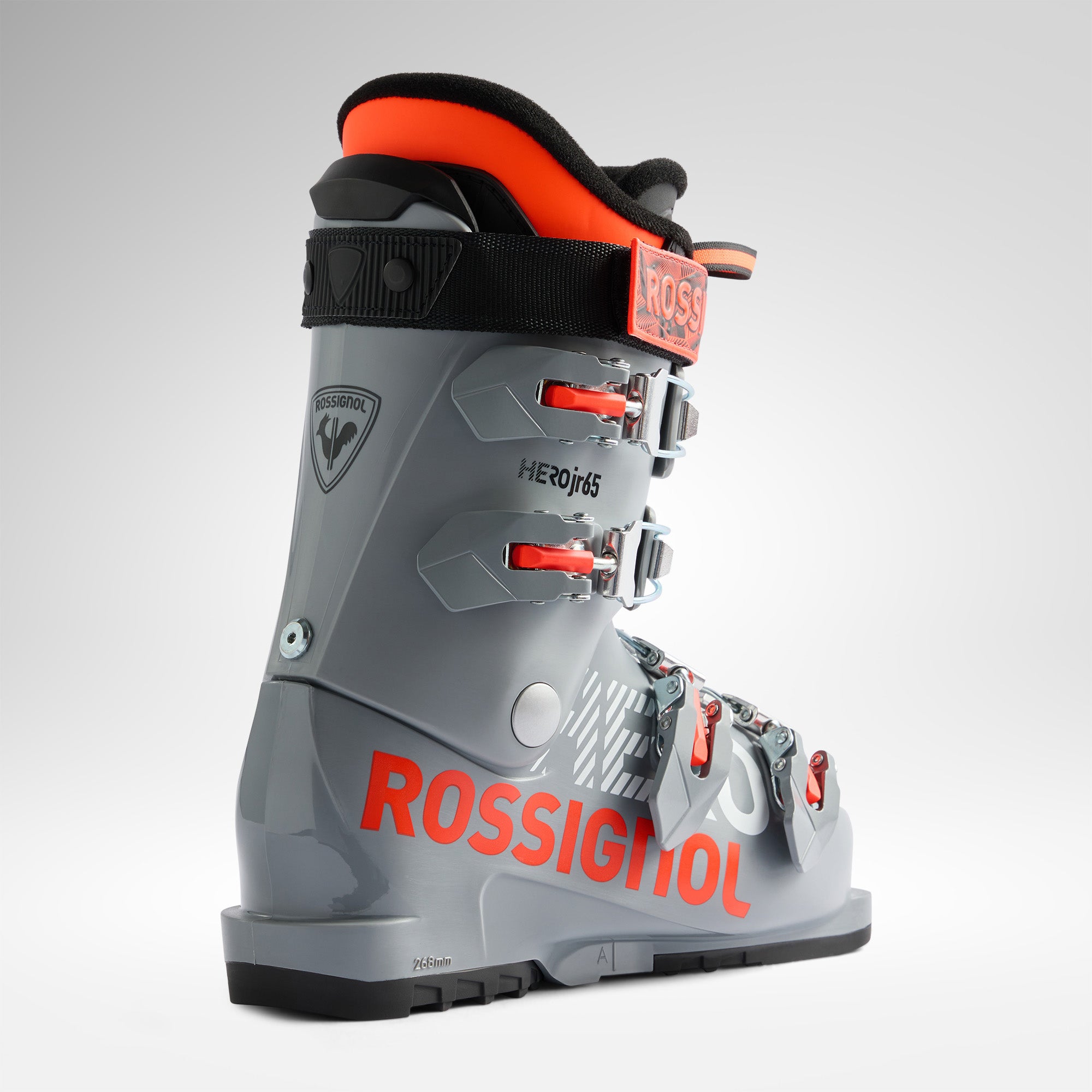 Der Rossignol HERO JR 65 - POWER GREY 2026/2027 Skischuh mit roten und schwarzen Akzenten, mehreren Schnallen und einem auffälligen ROSSIGNOL-Branding wird auf einem schlichten weißen Hintergrund präsentiert.