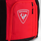 Nahaufnahme einer roten Rossignol HERO ATHLETES BAG mit einer Reißverschlusstasche, auf deren Vorderseite das weiße Rossignol-Logo und das Hahn-Emblem zu sehen sind.