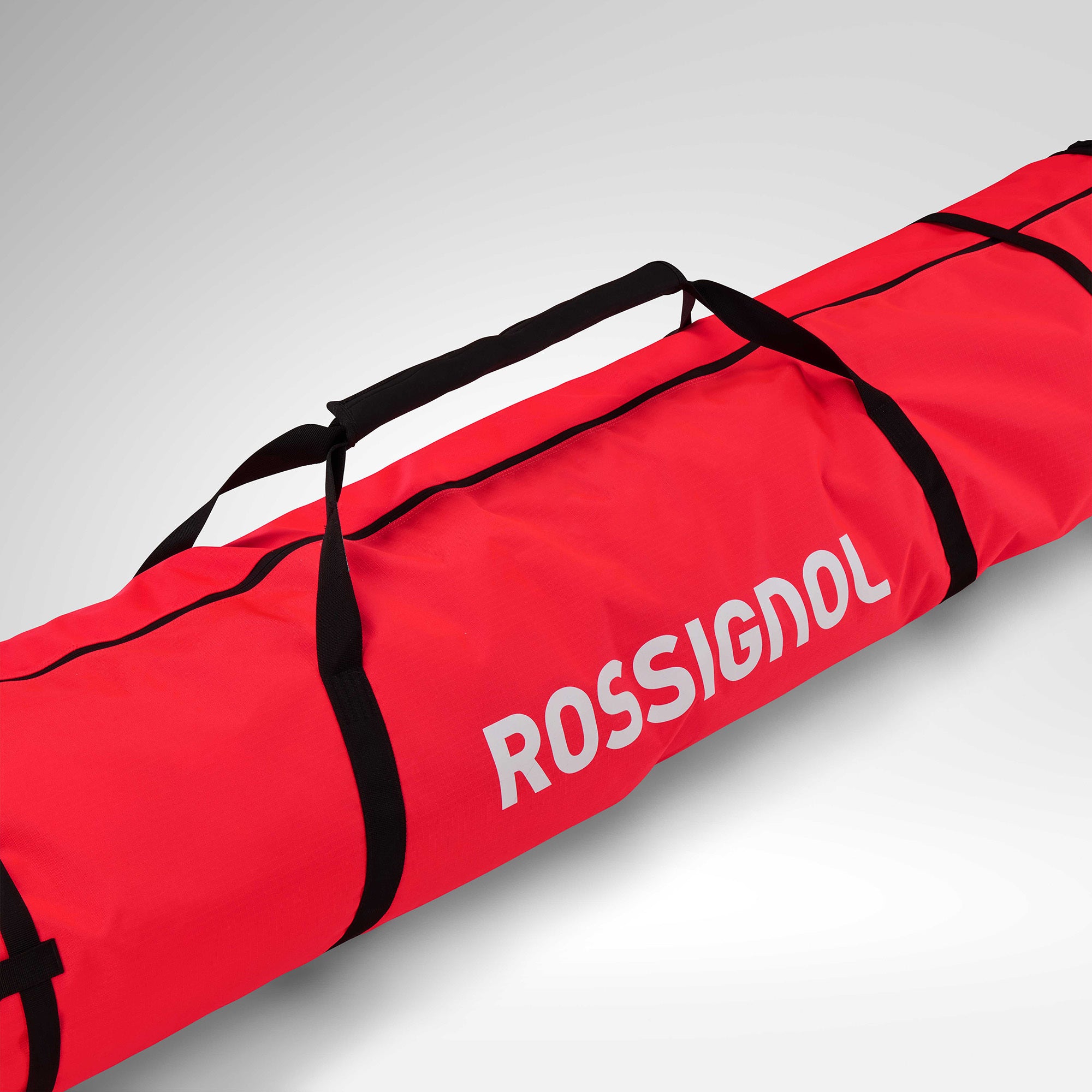 Die Rossignol HERO SKI BAG 2/3P ADJUSTABLE 190/220 ist in Rot mit schwarzen Griffen und Riemen vor einem hellen Hintergrund abgebildet. Das große Rossignol-Logo ist in fetten weißen Buchstaben an der Seite zu sehen, und die Tasche lässt sich für zusätzlichen Komfort in der Länge verstellen.