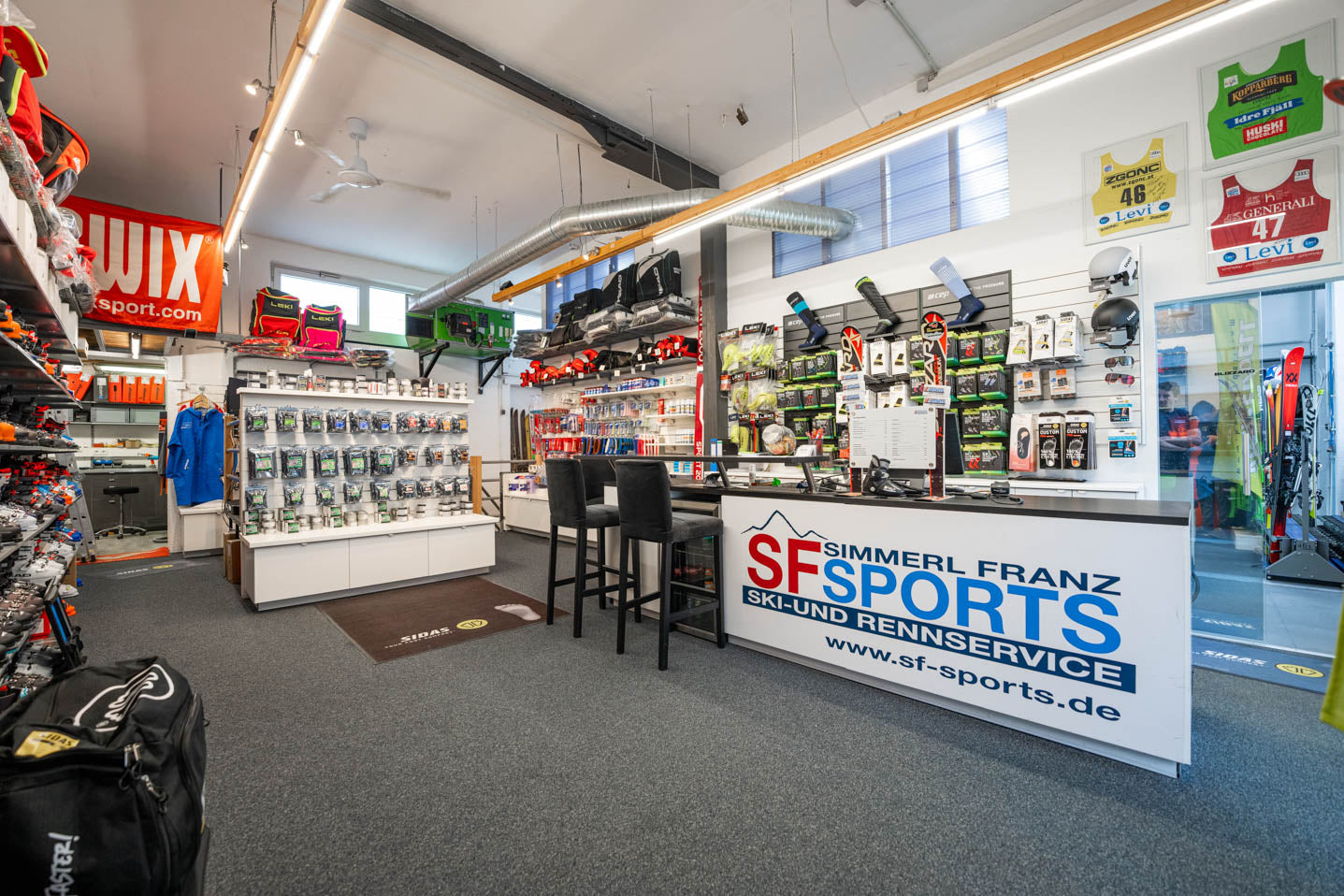 SF Sports Geschäft, ein Fachgeschäft in Gilching, spezialisiert auf Wintersportausrüstung für Skifahren und Snowboarding. Im Laden gibt es eine große Auswahl an Skiern, Snowboards, Skischuhen und Zubehör, die in einer modernen und einladenden Atmosphäre präsentiert werden.