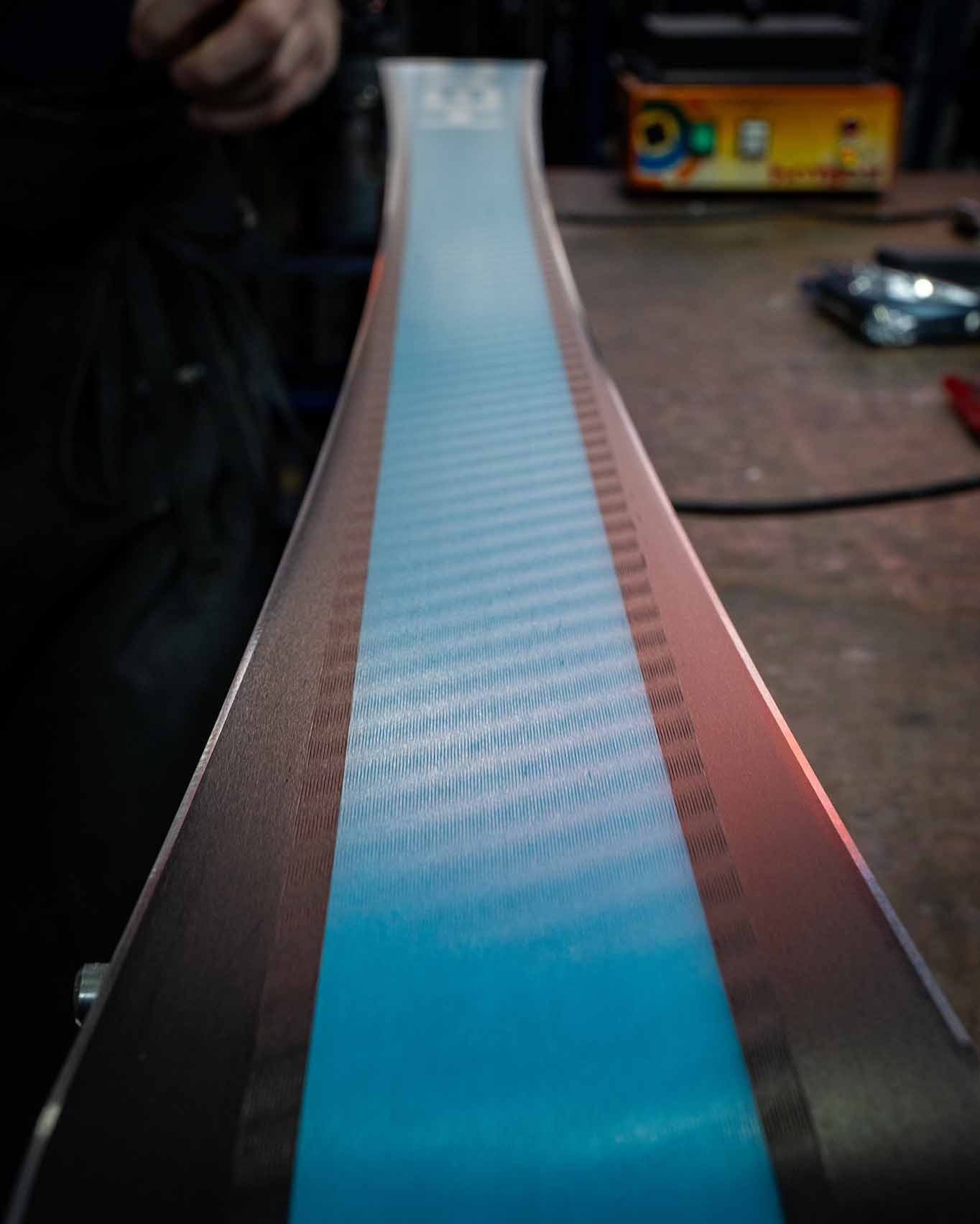 Detailaufnahme eines HEAD Rennskis mit frischer Struktur im Belag und präzise geschliffenen Kanten. Im Hintergrund sind Werkbank und Skiservicegeräte erkennbar – bereit für die nächsten Schritte der Skipräparation.