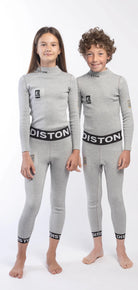 Zwei Kinder stehen nebeneinander und tragen passende DISTON Cut Resistant Top Junior - 4FIS Stars in CRG - CORE / Racing Fit Oberteile und Leggings von Diston. Sie posieren barfuß vor einem schlichten weißen Hintergrund.