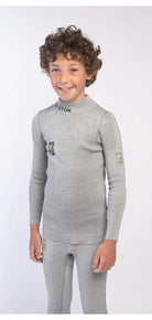 Ein lächelndes Kind mit lockigem Haar trägt das Diston DISTON Cut Resistant Top Junior - 3FIS Stars in CRG - BASE / Performance Fit mit kleinen Logos im Nacken, auf der Brust und am Arm vor einem schlichten weißen Hintergrund.