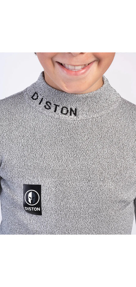 Ein lächelnder Kinderskifahrer zeigt das DISTON Cut Resistant Top Junior - 4FIS Stars in CRG - CORE / Racing Fit von Diston mit hellgrauem, strukturiertem Design, schwarzem Brustlogo und Markennamen am Kragen - ideale schnittfeste Unterwäsche für junge Rennfahrer.