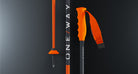 Drei orange-schwarze One Way RD 16 GS PRO-Skistöcke stehen senkrecht vor einem dunklen Hintergrund mit Farbverlauf. Der mittlere Stock trägt den Produktnamen, während der rechte Stock einen ergonomischen orangefarbenen Griff und eine verstellbare Schlaufe aufweist.