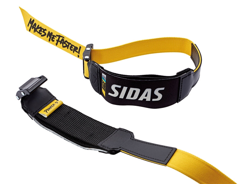 Der Sidas Sidas Powerstrap P1 verfügt über zwei gelbe und schwarze elastische Riemen mit dem Schriftzug "SIDAS" und "MAKES ME FASTER!", Schnallen und Polsterungen - Zubehör, das die Flexion des Skischuhs und die sportliche Leistung verbessert.