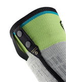 Eine Nahaufnahme eines grau-grünen Strickärmels mit zwei schwarzen Druckknöpfen und schwarzem Besatz, der ein Etikett mit goldenem Text und einem blauen Streifen aufweist. Inspiriert von den SIDAS Ski Race S.E.T. Socken, spiegelt es die Qualität von Sidas wider.