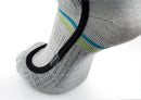 Nahaufnahme eines Fußes, der Sidas SIDAS Ski race S.E.T. Socken trägt - grau mit blauen und grünen Streifen, schwarzer strukturierter Griff entlang des Fußgewölbes -, die an Hochleistungsskisocken erinnern. Vor einem weißen Hintergrund.